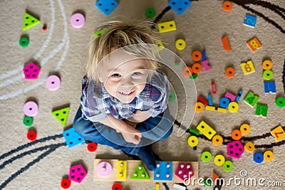 Little blonde toddler child, boy playing with wooden toys developing and learning Stock Photo