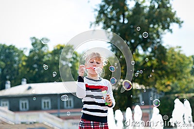 Little blondy girl playing with soap bubbles in summer park Stock Photo