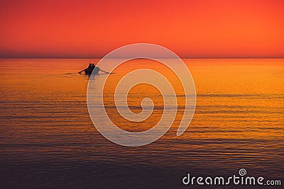 little boat in a sea red orange sky at sunset Stock Photo