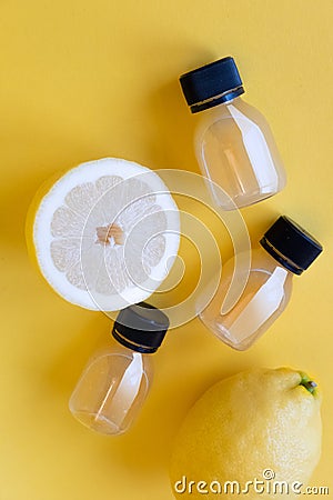 Little bottle of lemon juice and fresh lemons. Isolated on yellow background. Citrus Juice Concept, Vitamin C, Fruits. Stock Photo