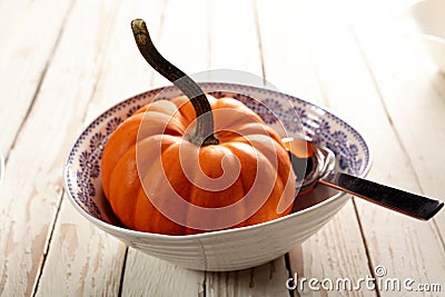 Little bowl with tiny pumpkin and spoon Stock Photo