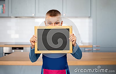 little boy in apron holding chalkboard in kitchen Stock Photo