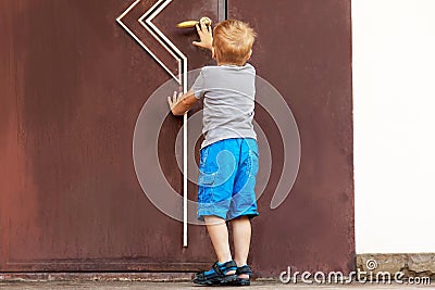 Caucasian baby boy tries to open the big door. Stock Photo