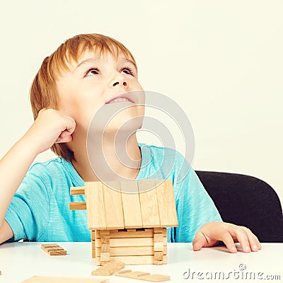 Little boy builds house from wooden blocks. My house concept. Concept of dream home and mortgage investment. Little boy playing as Stock Photo