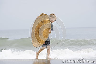 Little Boy Carrying Bodyboard In Sea Stock Photo