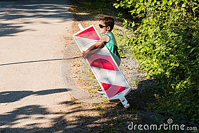 Little boy is carrying a construction site barrier Stock Photo