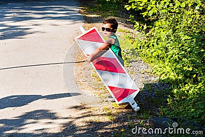 Little boy is carrying a construction site barrier Stock Photo