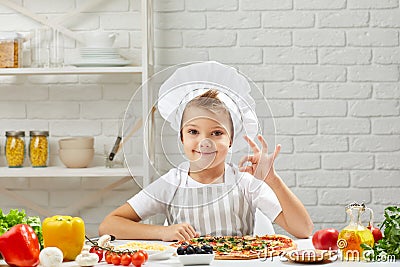 Little boy in chef hat and an apron cooking pizza Stock Photo