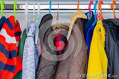 Little boy child size jackets, coats and sweaters hanging in a kid`s closet with colorful hangers Stock Photo