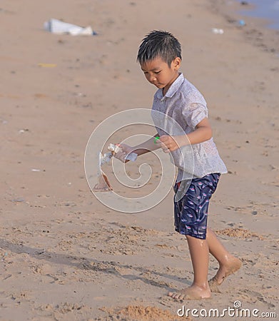 Little boy cleaning up garbage and plastic waste on the beach for enviromental clean up and ecology conservation concept Stock Photo