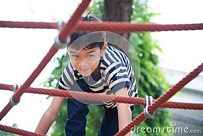 Little boy climbing rope at playground Stock Photo