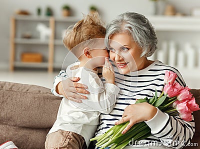 Little boy congratulating grandmother with flowers Stock Photo