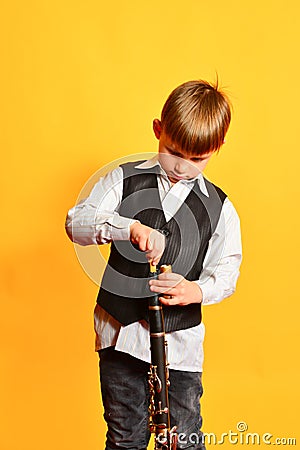 A little boy in costume tunes the clarinet before playing the music scene Stock Photo