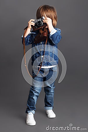 A little boy in denim tries to take a shoot using a vintage camera. Stock Photo