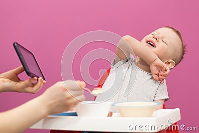 Little boy does not want to eat Mashed potatoes. Child eats breakfast at home, while watching cartoon on tablet Stock Photo