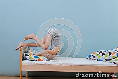 Little boy doing morning gymnastics in unmade bed. Forward roll exercise Stock Photo