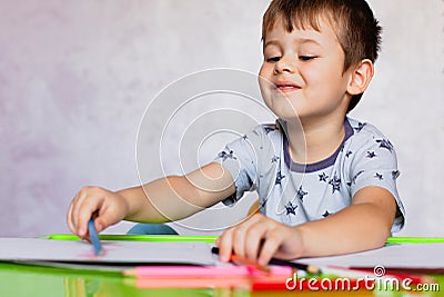 Little boy drawing with color pencils. Boy, drawing a picture for fathers day. Small boy draws at the table Stock Photo