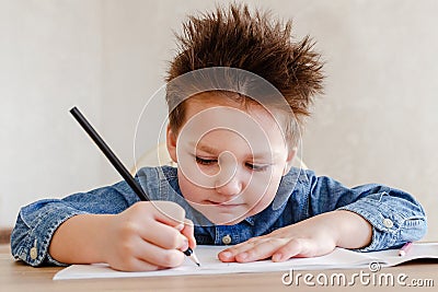 Little boy draws with a color pencil at the table Stock Photo