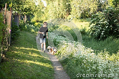 Little boy and favorite companion dog coker spaniel friend walking in garden, trees, flowers, street. Light day outdoor Stock Photo