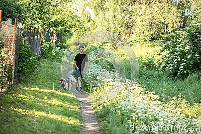 Little boy and favorite companion dog coker spaniel friend walking in garden, trees, greenery, street. Light day outdoor Stock Photo