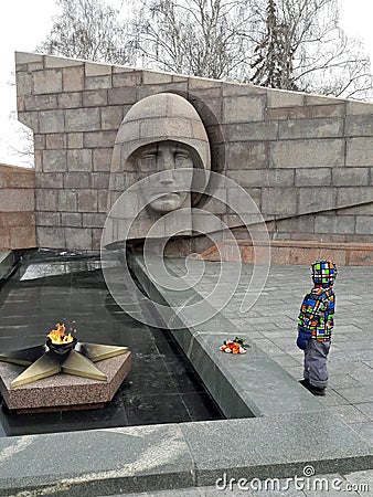 Little boy with flowers on the holiday of May 9 the day of victory in Second world war USSR near monument to unknown soldier Editorial Stock Photo