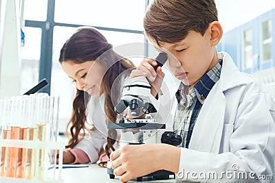 Little kids learning chemistry in school laboratory microscope experiment Stock Photo