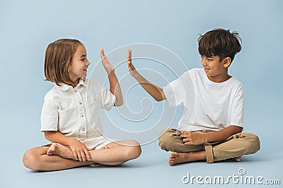 Little boy and girl of roughly the same age sitting on the floor cross-legged Stock Photo