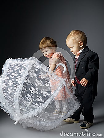 Little boy and girl sitting under umbrella Stock Photo