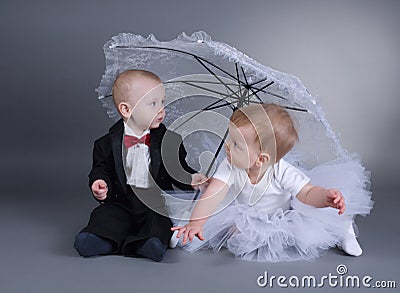 Little boy and girl sitting under umbrella Stock Photo