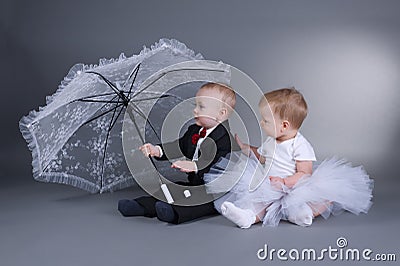 Little boy and girl sitting under umbrella Stock Photo