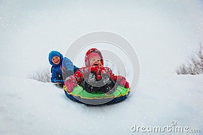 Little boy and girl slide in winter snow Stock Photo