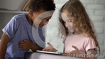 Little boy and girl watching movie on tablet at kindergarten, early development Stock Photo