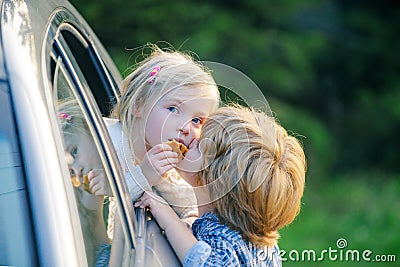 Little boy gives kiss for cute girl. Bye bye. Funny little couple saying goodbye before car travel. Farewell child Stock Photo