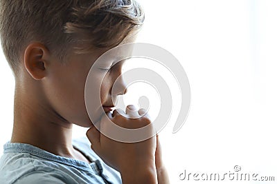 Little boy with hands clasped together for prayer on light background. Stock Photo