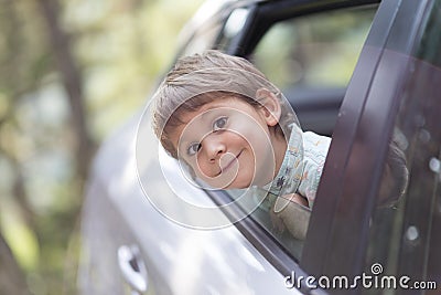 Little boy with head leaned through the open window of a car Stock Photo