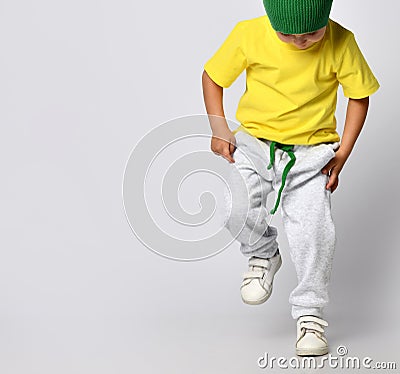 Little boy hip-hop dancer in bright pants and a green hat looks down Stock Photo