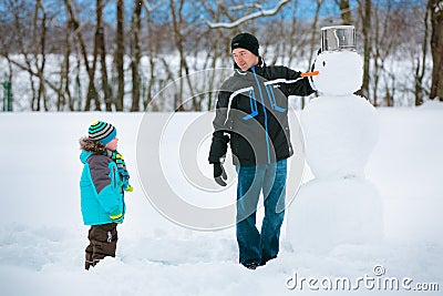 Little boy with his father making a snowman Stock Photo