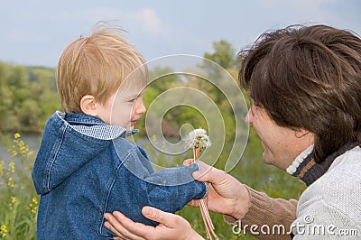 Little boy and his father play with dandelions Stock Photo