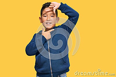 Little boy hispanic kid wearing casual sporty jacket smiling making frame with hands and fingers with happy face Stock Photo