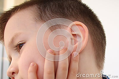 Little boy holds on to the ear, part of the face close-up, medical concept, hearing control, middle ear inflammation, otitis media Stock Photo