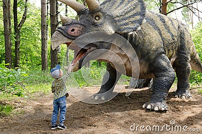 Little boy interacts with dinosaur model Triceratops Editorial Stock Photo