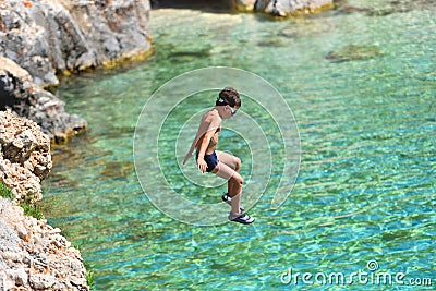 Little boy jumping off cliff into the ocean. Summer fun lifestyle. Brave kid Stock Photo