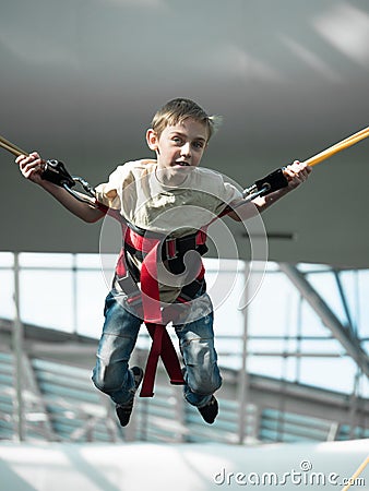 Little boy jumping on the trampoline with rubber ropes Stock Photo