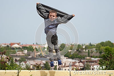 Little boy jumping up revealing jacket like wings Stock Photo