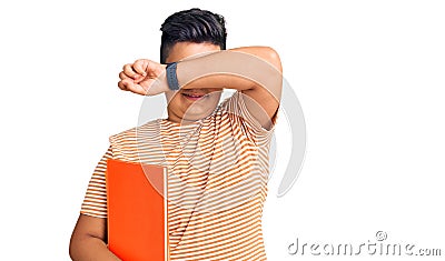 Little boy kid holding book wearing glasses smiling cheerful playing peek a boo with hands showing face Stock Photo