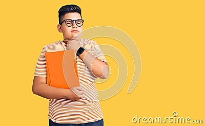 Little boy kid holding book wearing glasses touching painful neck, sore throat for flu, clod and infection Stock Photo