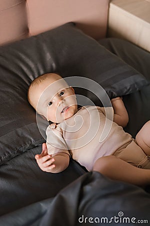 Little boy kid is lying on dark bedding on the bed Stock Photo