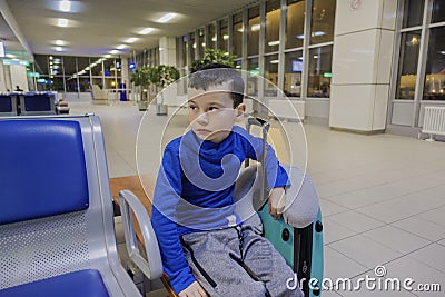 Young boy sitting alone in a corridor of airport at feeling sad mood. Stock Photo