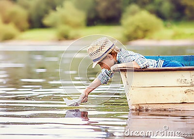 Little boy launch paper ship from old boat on the lake Stock Photo