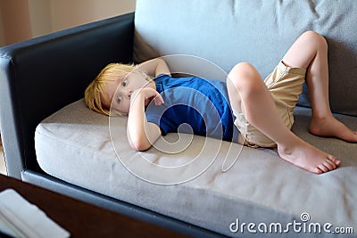 Little boy laying on couch and watching cartoons by tablet pc. Kids and gadgets. Addiction Stock Photo